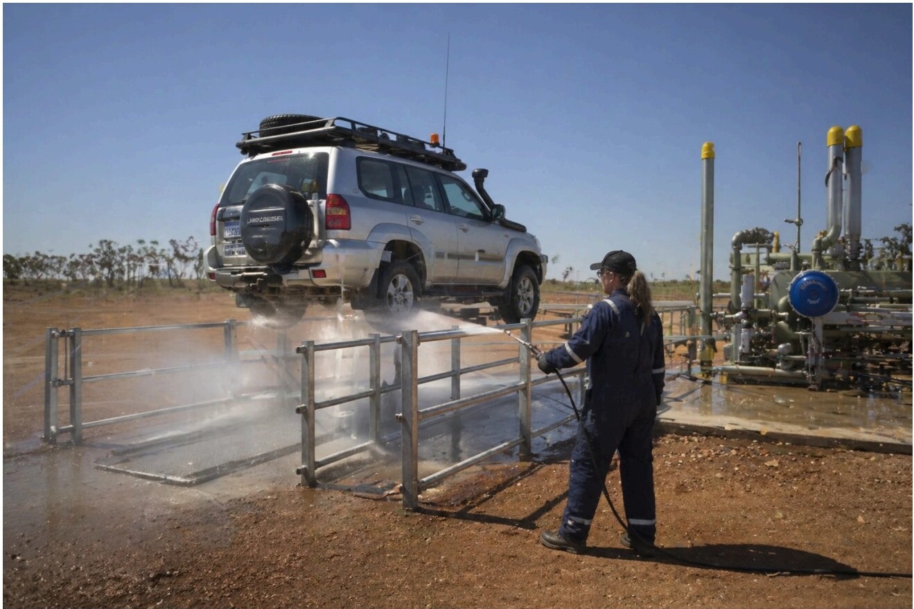 Worker spraying down a vehicle at a washdown station
